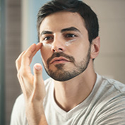 Metrosexual man applying lotion for anti-aging treatment around eye